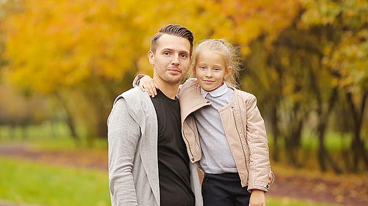 爸爸抱着个可爱的小女孩在公园里享受秋天视频的预览图