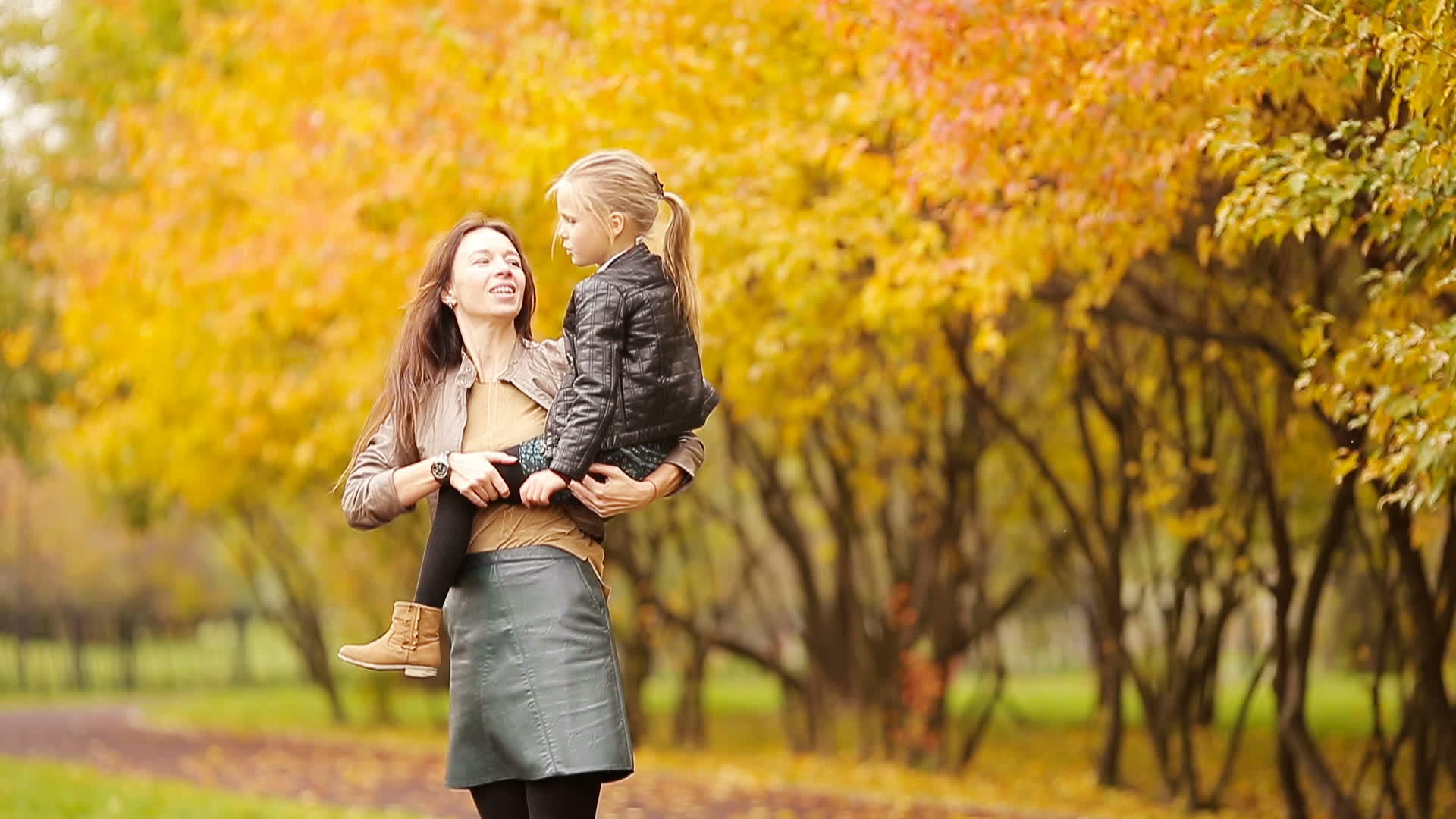 母亲抱着可爱的小女孩享受秋天的公园视频的预览图