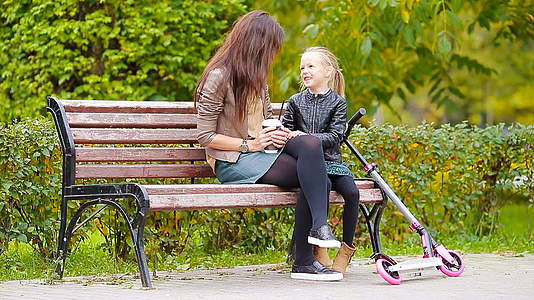 母亲和可爱的小女孩享受秋天的公园视频的预览图
