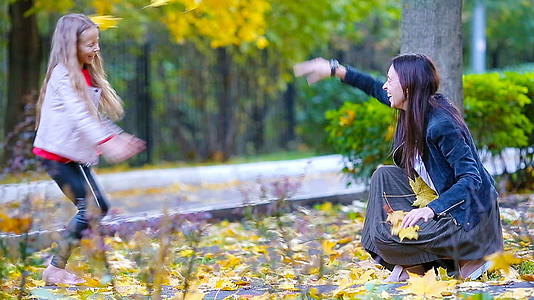 秋天公园里可爱的小女孩和快乐的母亲视频的预览图