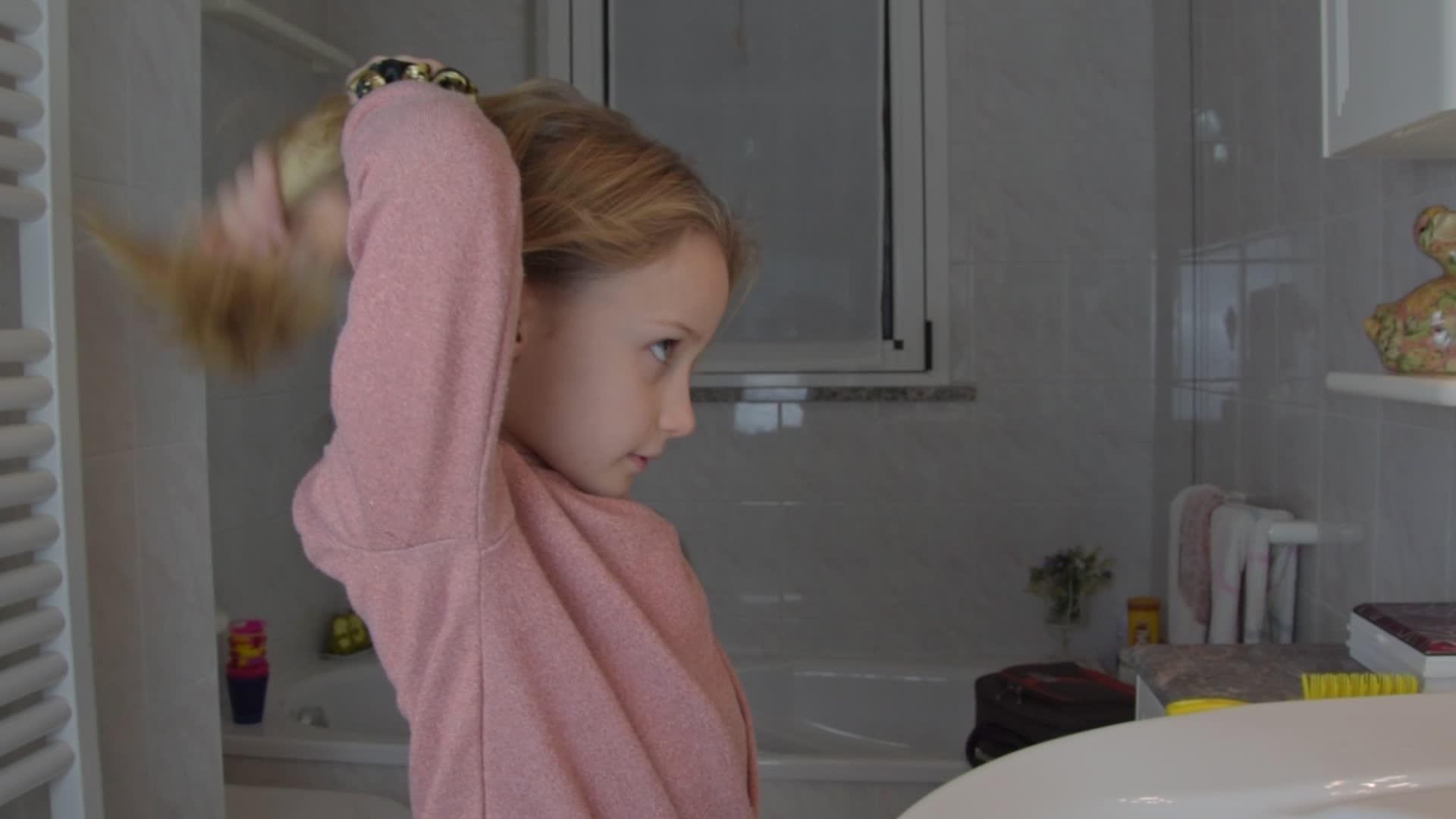 家里浴室里穿着粉色衬衫的金发女孩视频的预览图