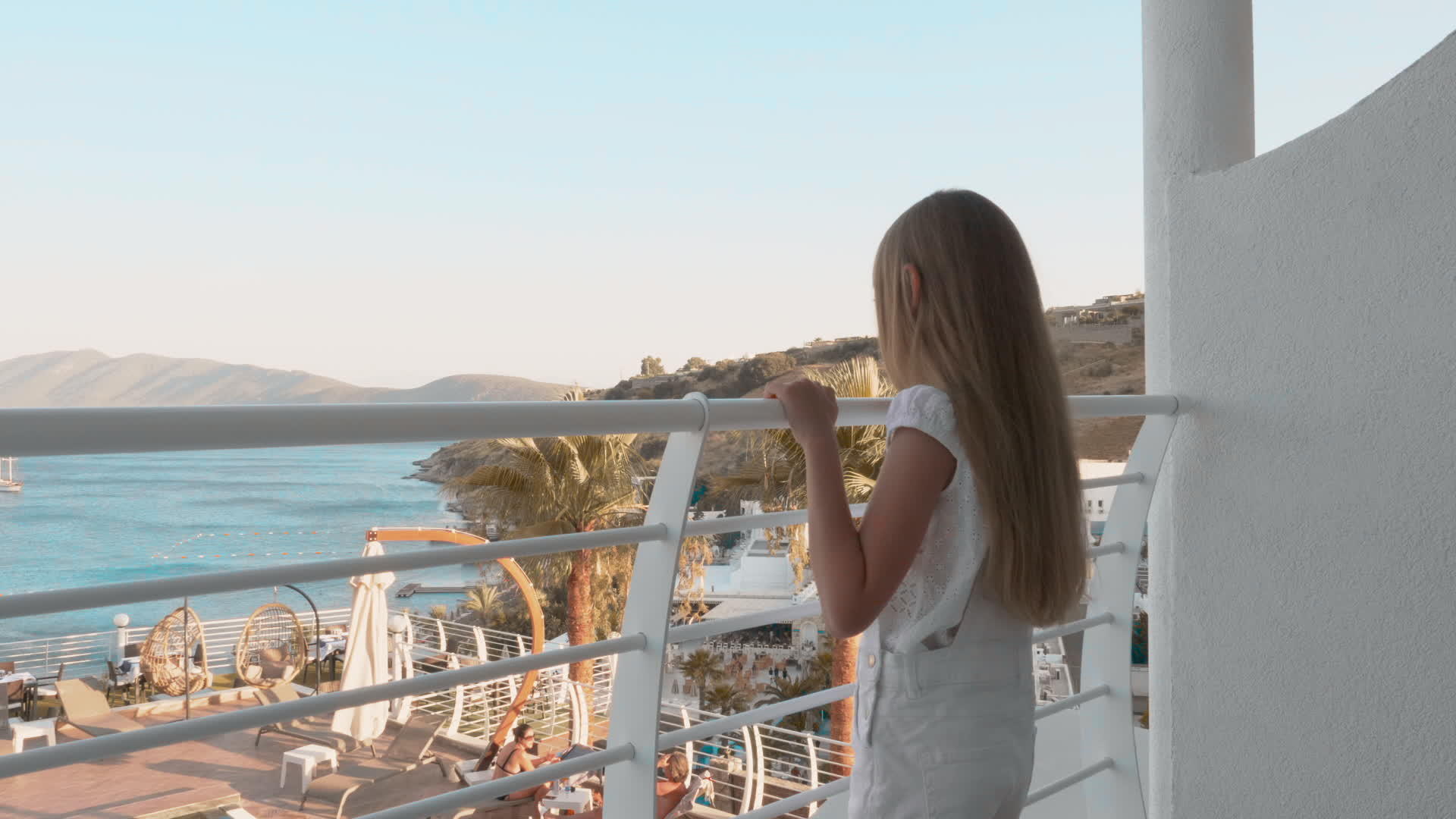 可爱的女孩站在阳台上看海景视频的预览图