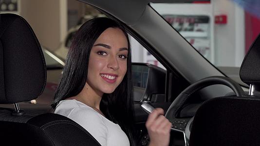这位美丽快乐的女士坐在她的新车里展示了车钥匙视频的预览图