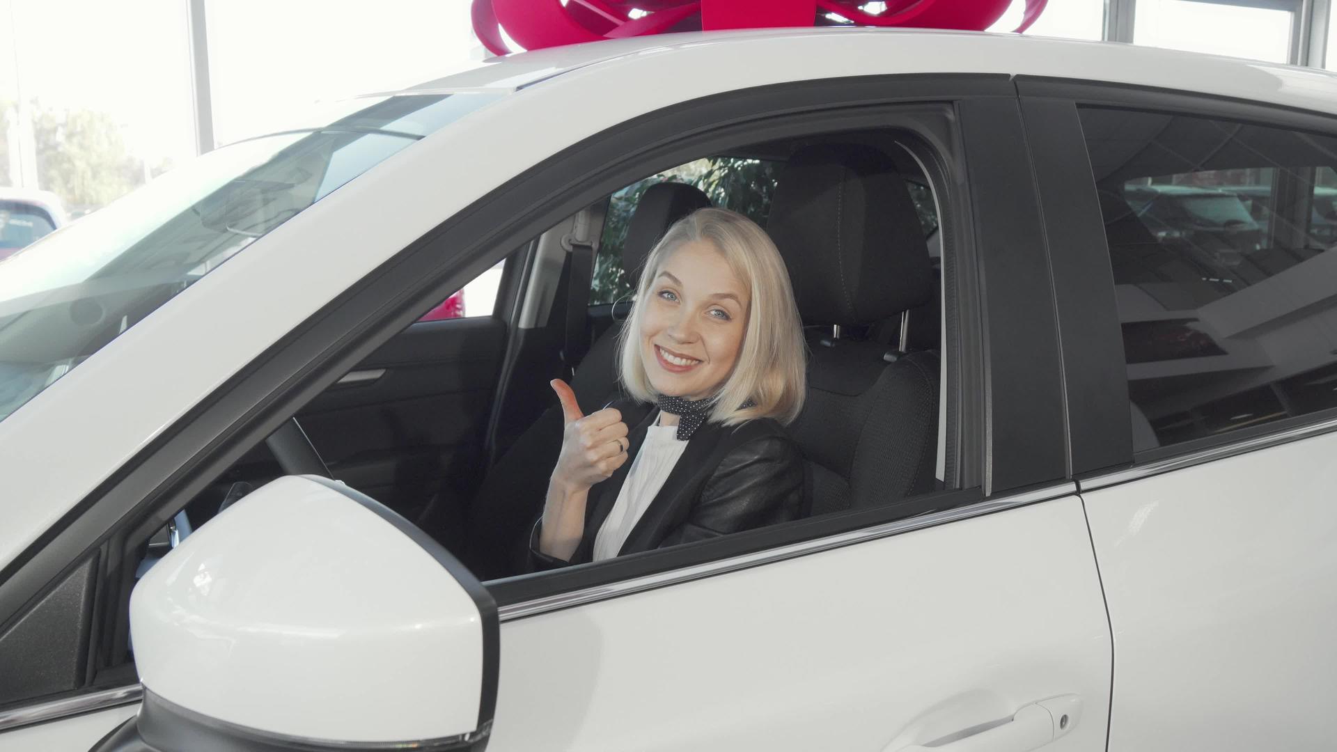 快乐的女士坐在她的新车里举起拇指视频的预览图