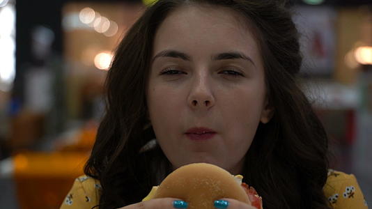 女孩在食物法庭上吃汉堡视频的预览图