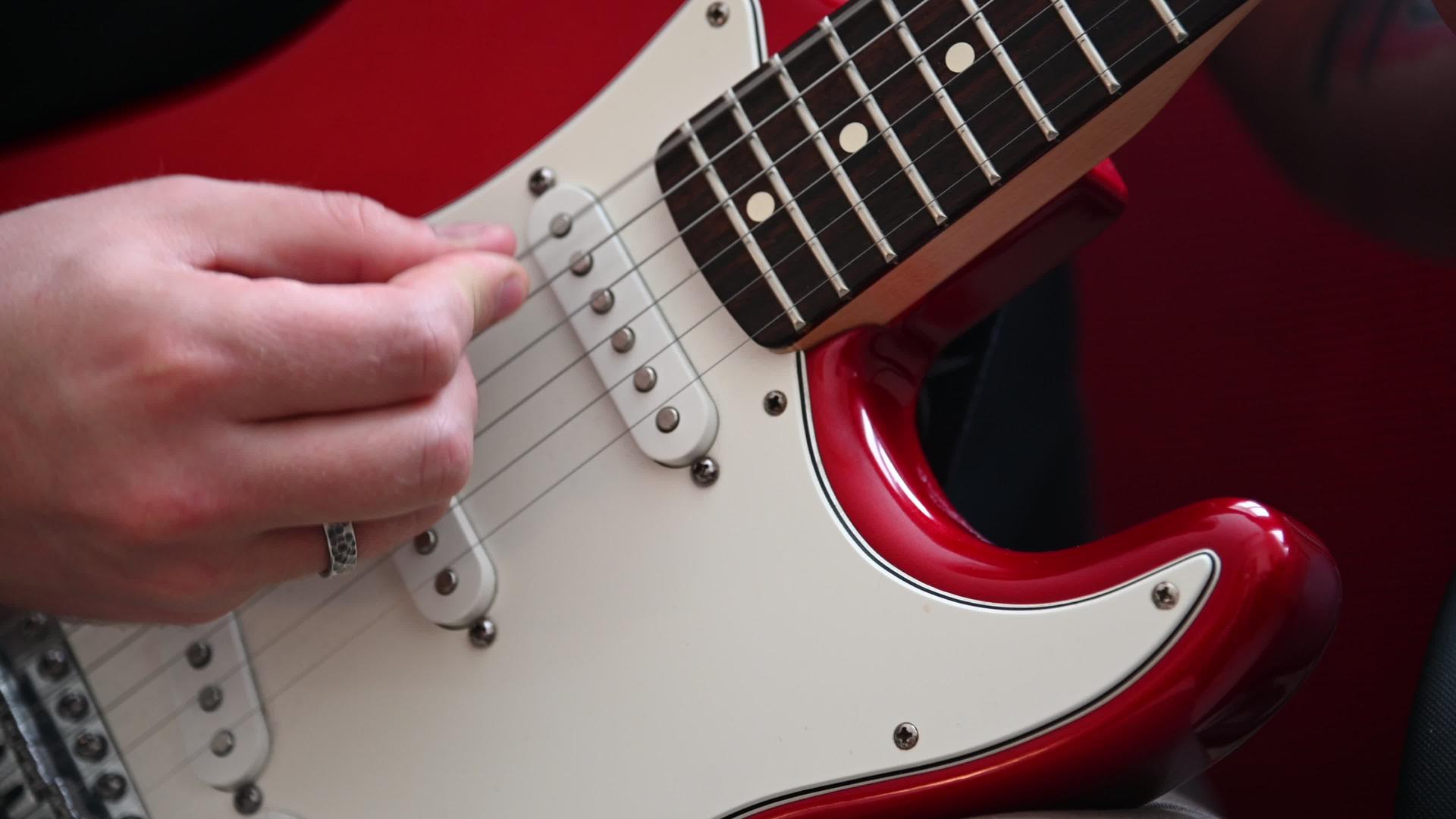 男人玩红色电吉他的近镜头视频的预览图