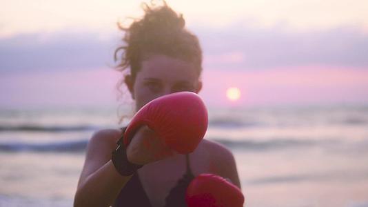 女子在海边的空手道上进行运动训练以防止日落视频的预览图