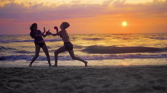女子运动在海边训练空手道在日落和慢动作之前视频的预览图