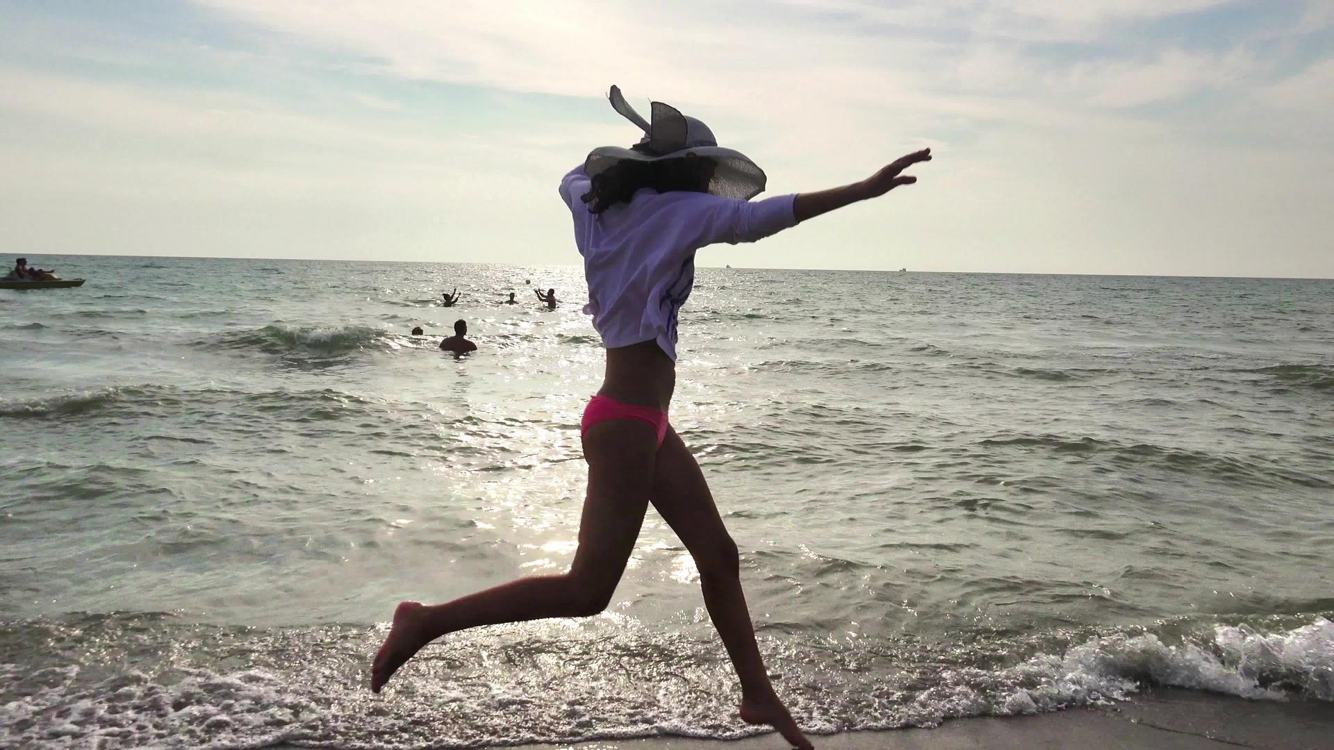日落时年轻女孩在海滩上奔跑她的手臂伸展自由跳舞被波浪冲浪视频的预览图