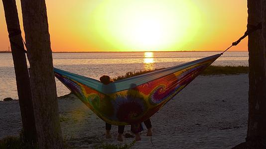 日落时彩色吊床的女夫妇视频的预览图