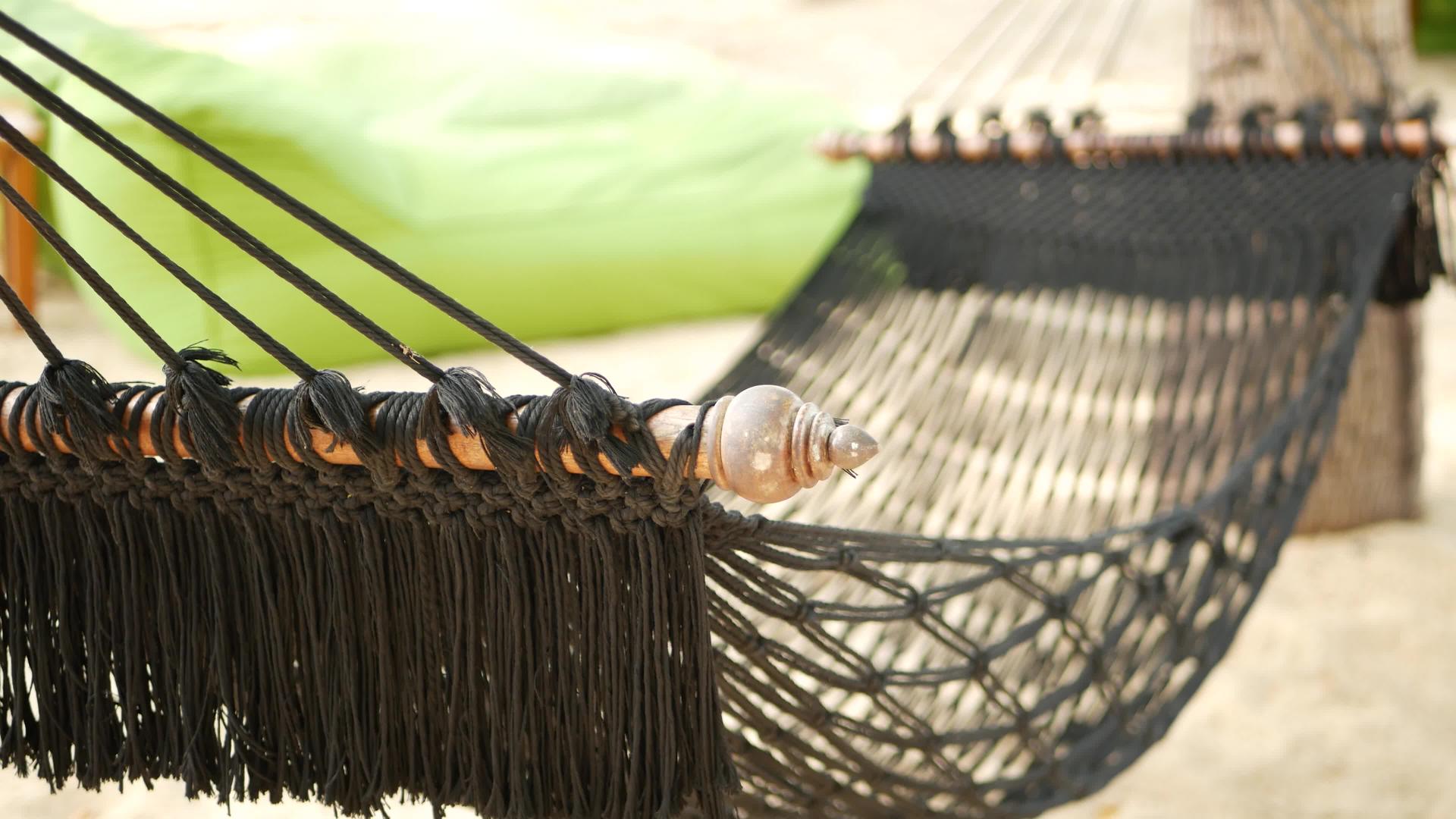 椰子树之间的黑色吊床伸展在网状复古时尚吊床的边缘视频的预览图