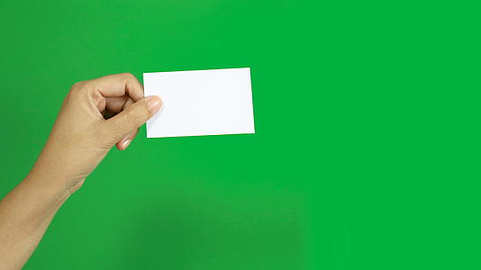 女性在色度键绿色屏幕背景下展示空白名片纸视频的预览图