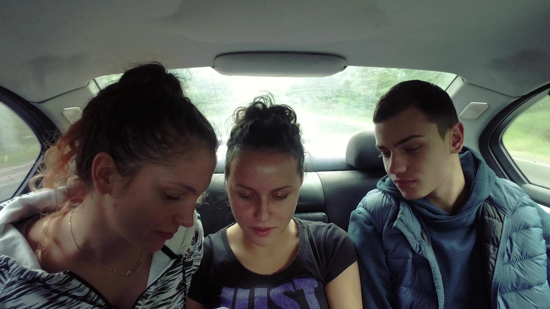 三个年轻人在车里看着智能手机视频的预览图