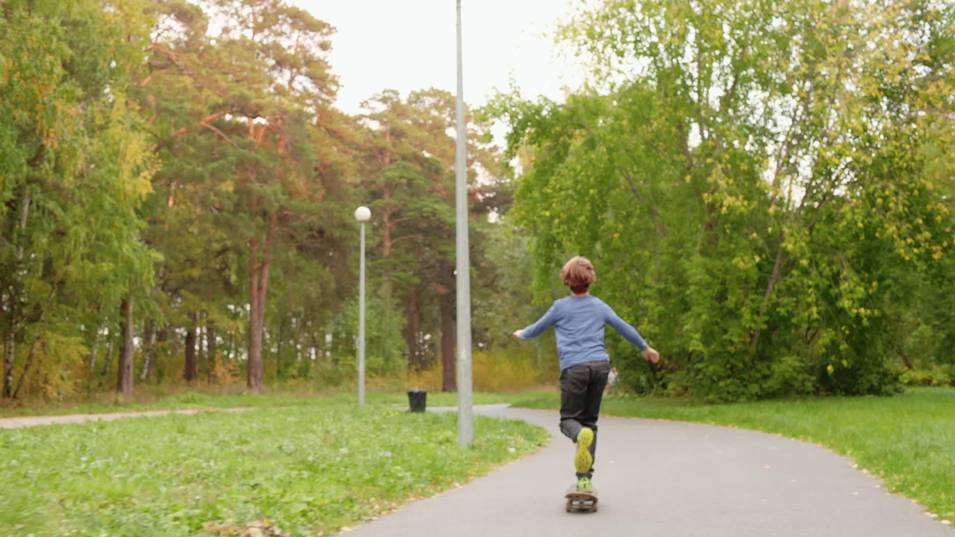 可爱的年轻男孩在美丽的绿色公园里骑滑板视频的预览图