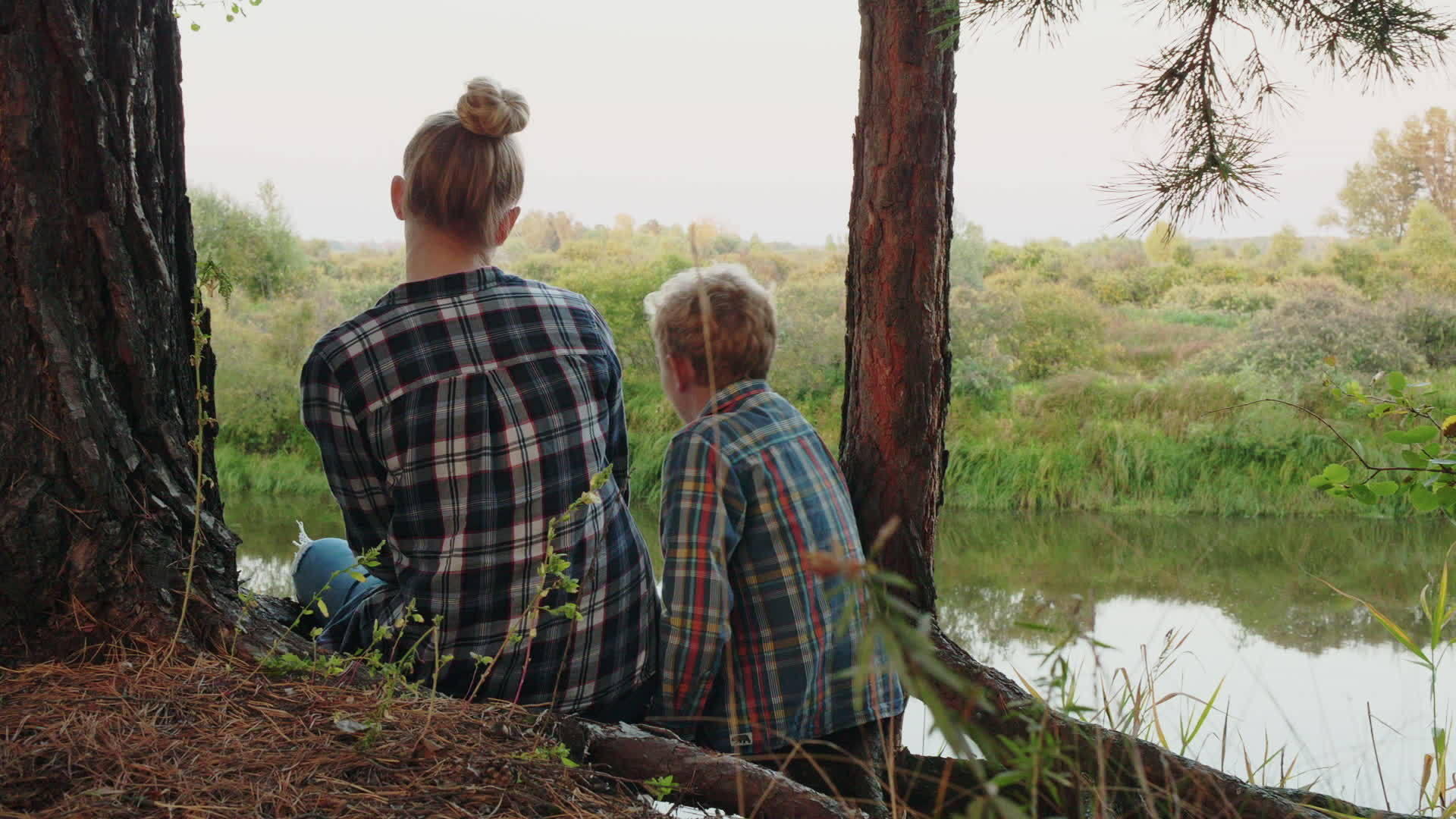 男孩和女孩坐在河边拥抱的后面视频的预览图