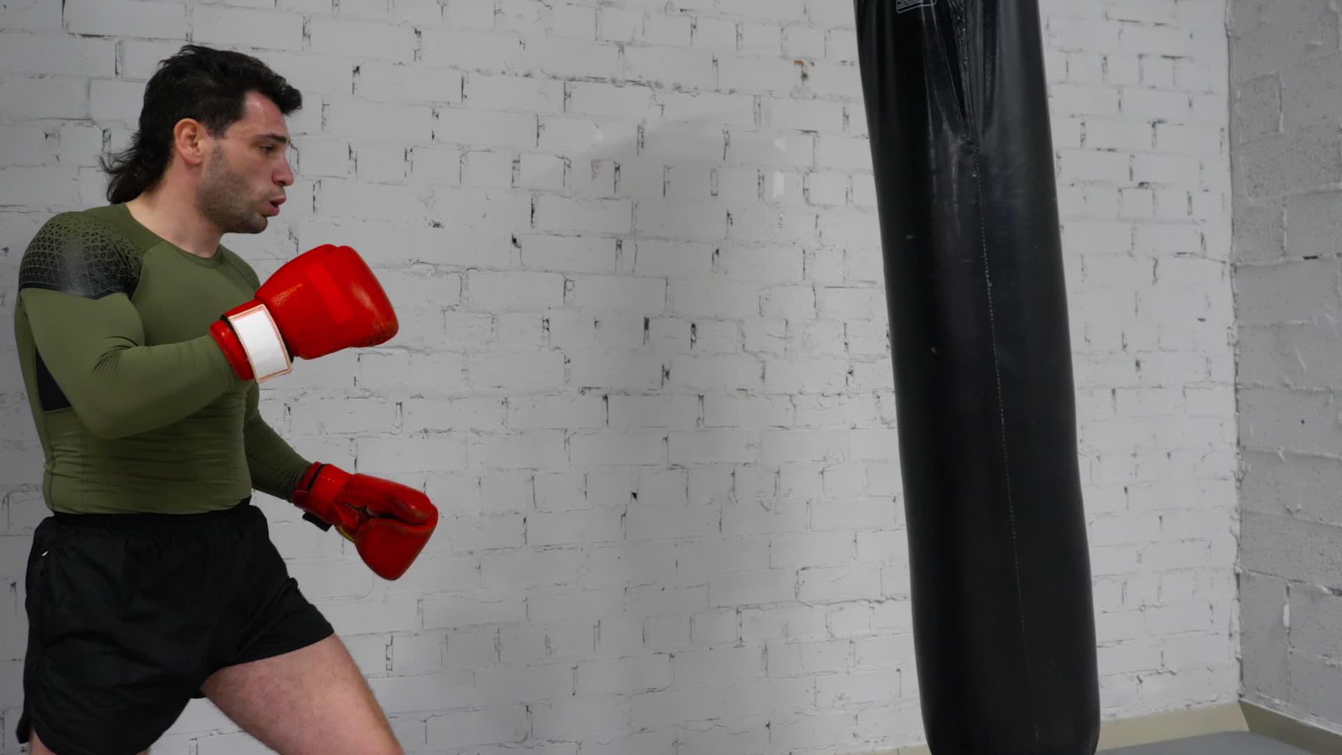 男子拳击手在手套训练中踢拳头袋视频的预览图