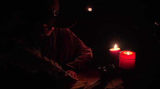 魔术师用羽毛笔和墨水在纸上点燃蜡烛视频的预览图
