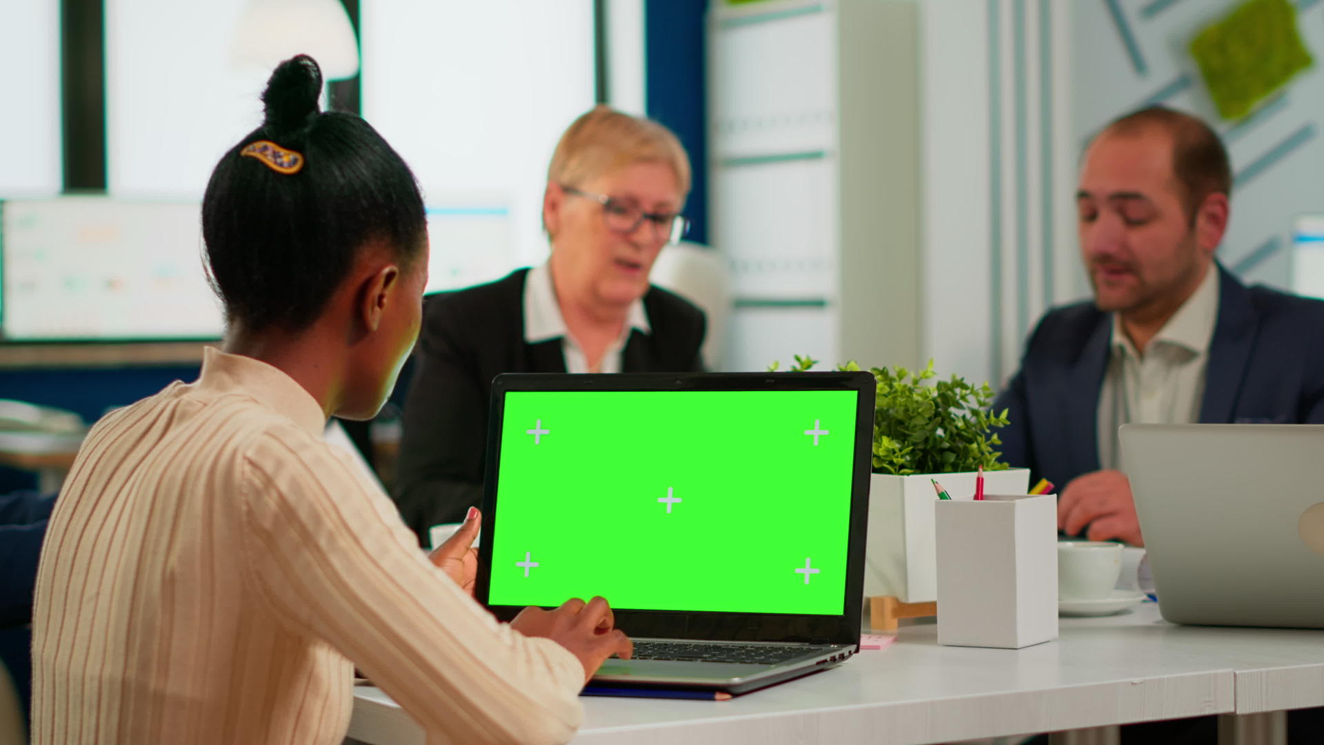 坐在会议桌旁的非洲女经理用绿色屏幕看着笔记本电脑视频的预览图