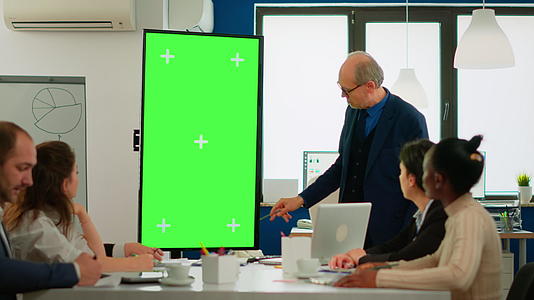 会议室里成熟的商人分析报告站指向绿屏监视器视频的预览图
