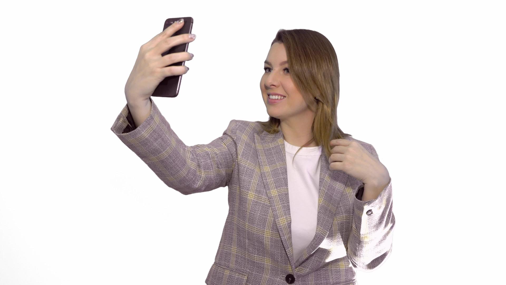 穿着夹克的快乐微笑的金发女性金发女性在智能手机中使用白色机器视频的预览图