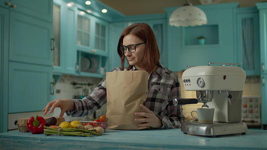 戴眼镜的年轻成年女性在家里拿着纸袋和新鲜食物视频的预览图