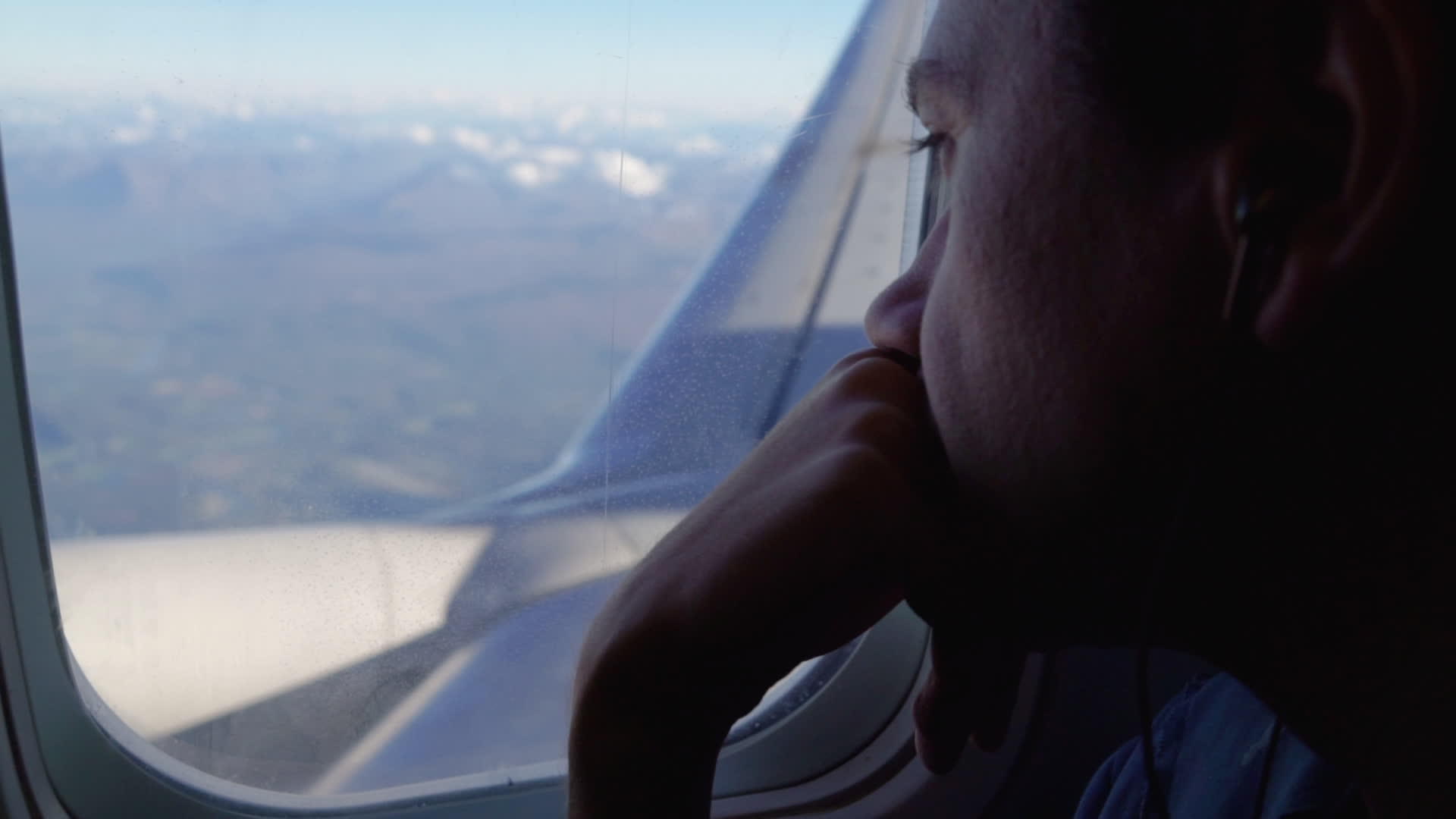 戴着耳机的白人男子在飞机窗口仔细观察视频的预览图