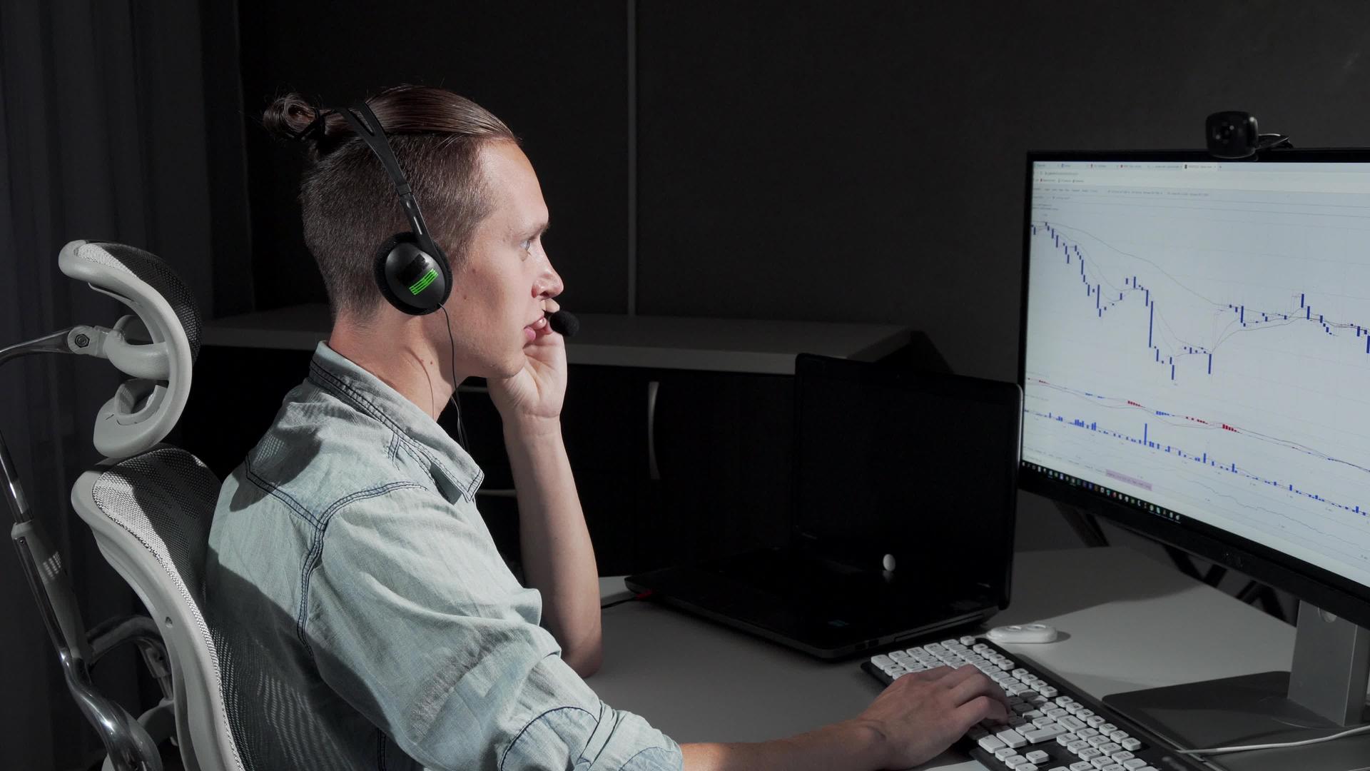 年轻男子在晚上使用耳机和麦克风在网上工作视频的预览图