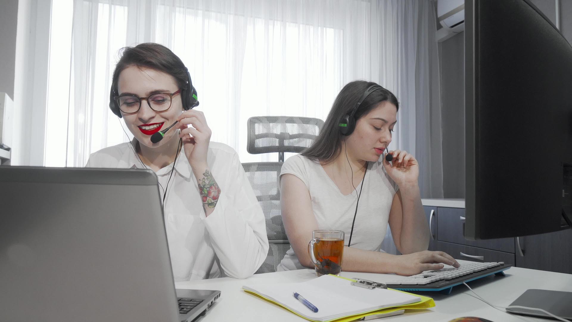 两名女呼叫中心的女服务员在她们的电脑上工作视频的预览图