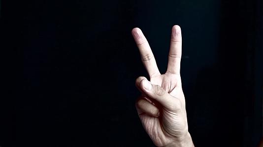 在黑色背景上显示胜利或和平标志的手视频的预览图