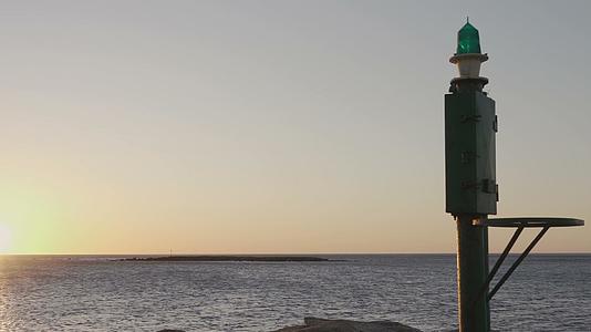 港口前有一个小灯塔可以看到日出、日落和日落时的海洋视频的预览图