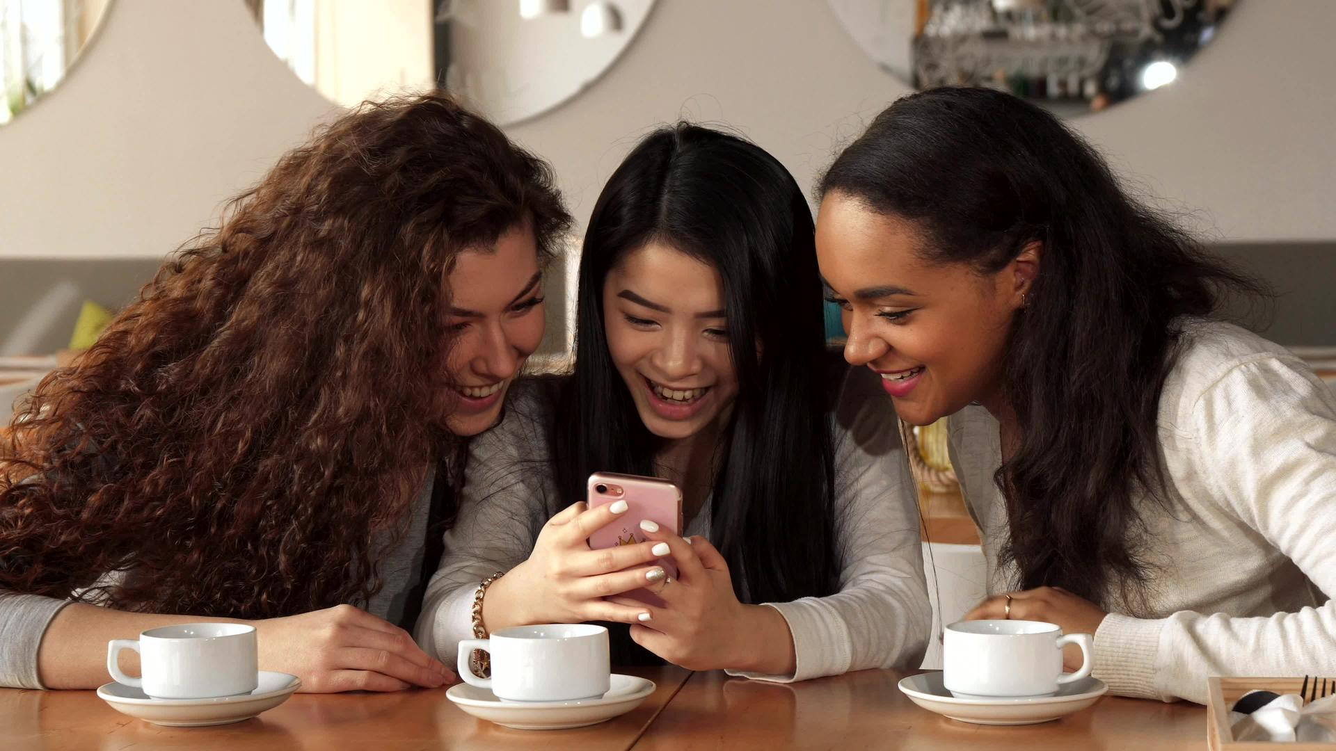三个女孩在咖啡馆的智能手机上看了一些东西视频的预览图