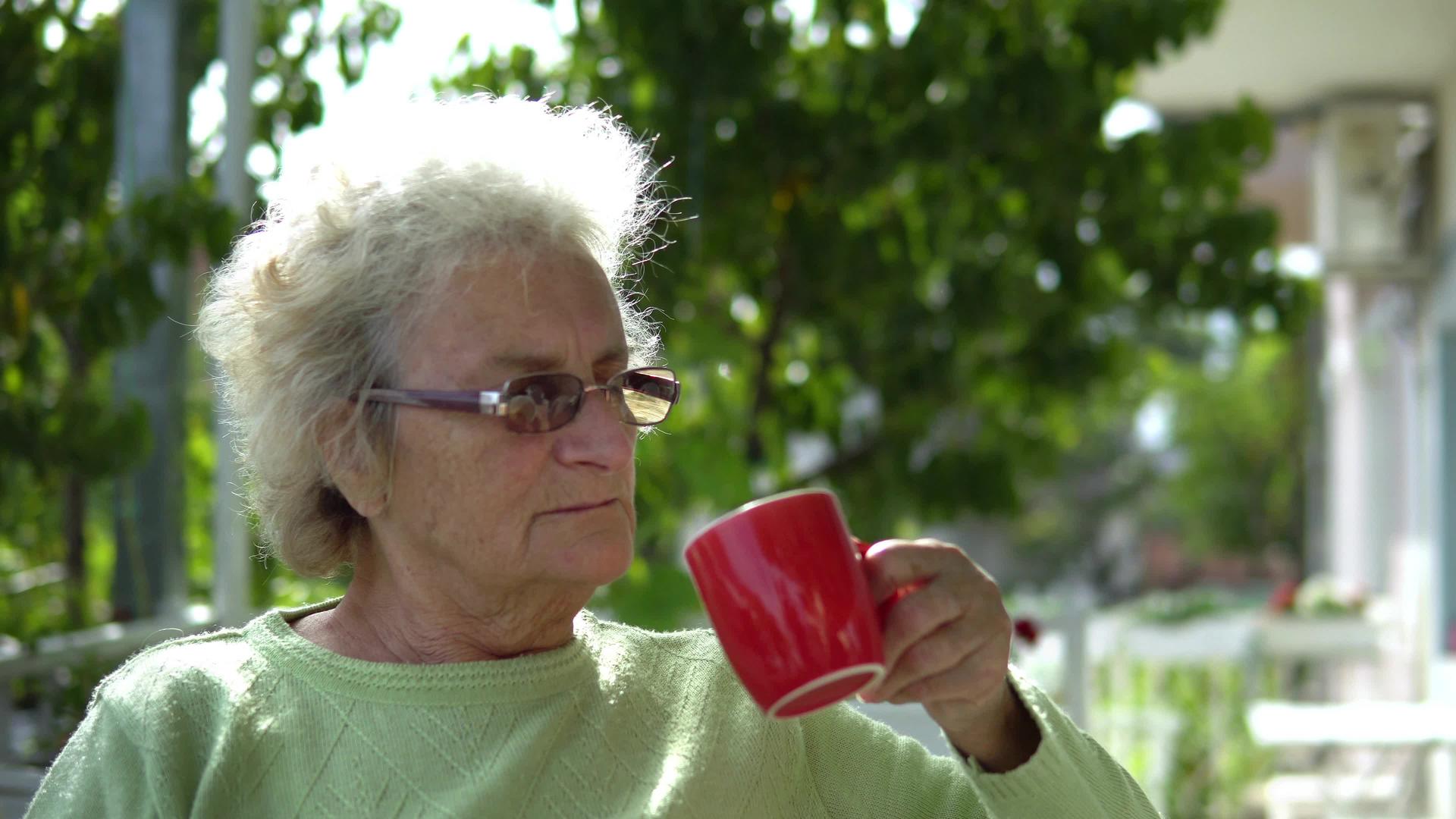 老年妇女坐在户外喝咖啡茶视频的预览图