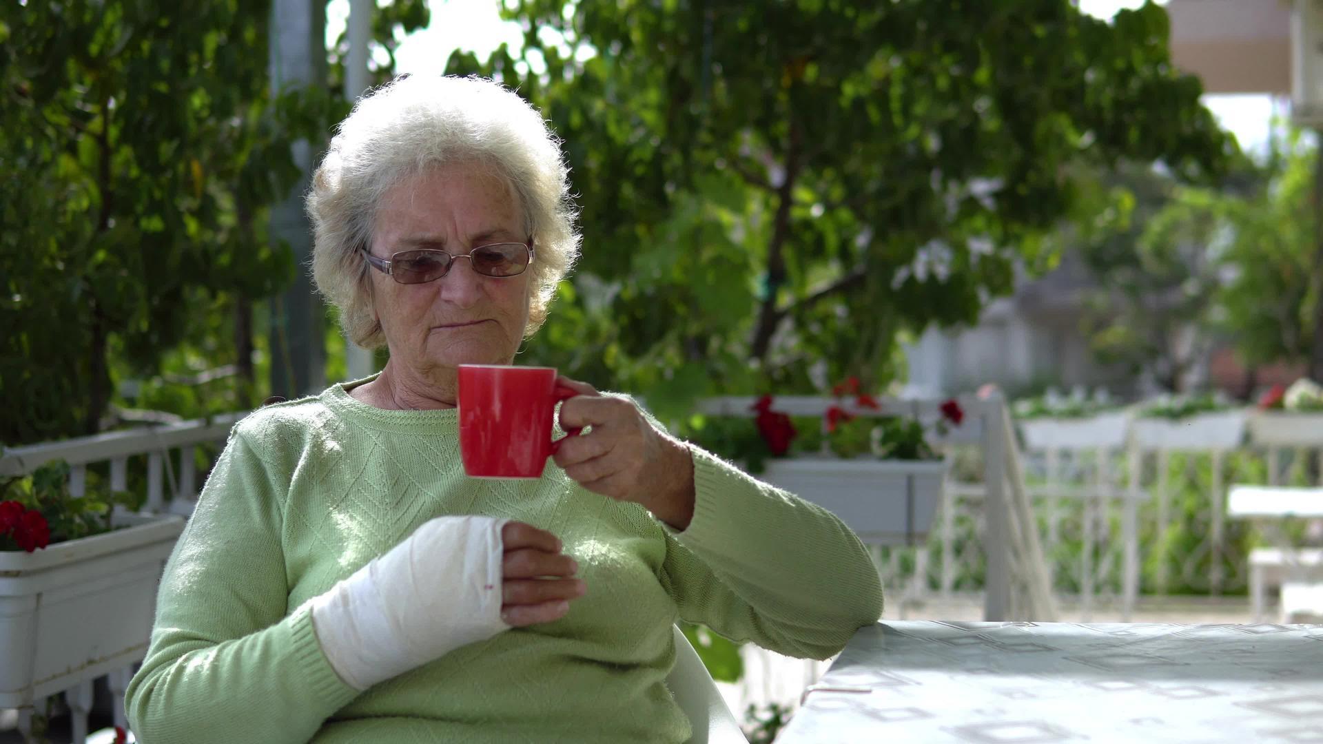 受伤的老年妇女在户外喝咖啡视频的预览图