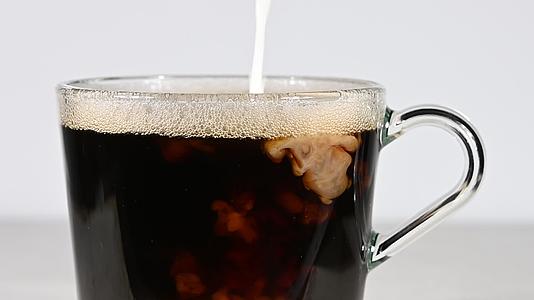 把牛奶倒入黑色咖啡杯中的玻璃杯中视频的预览图