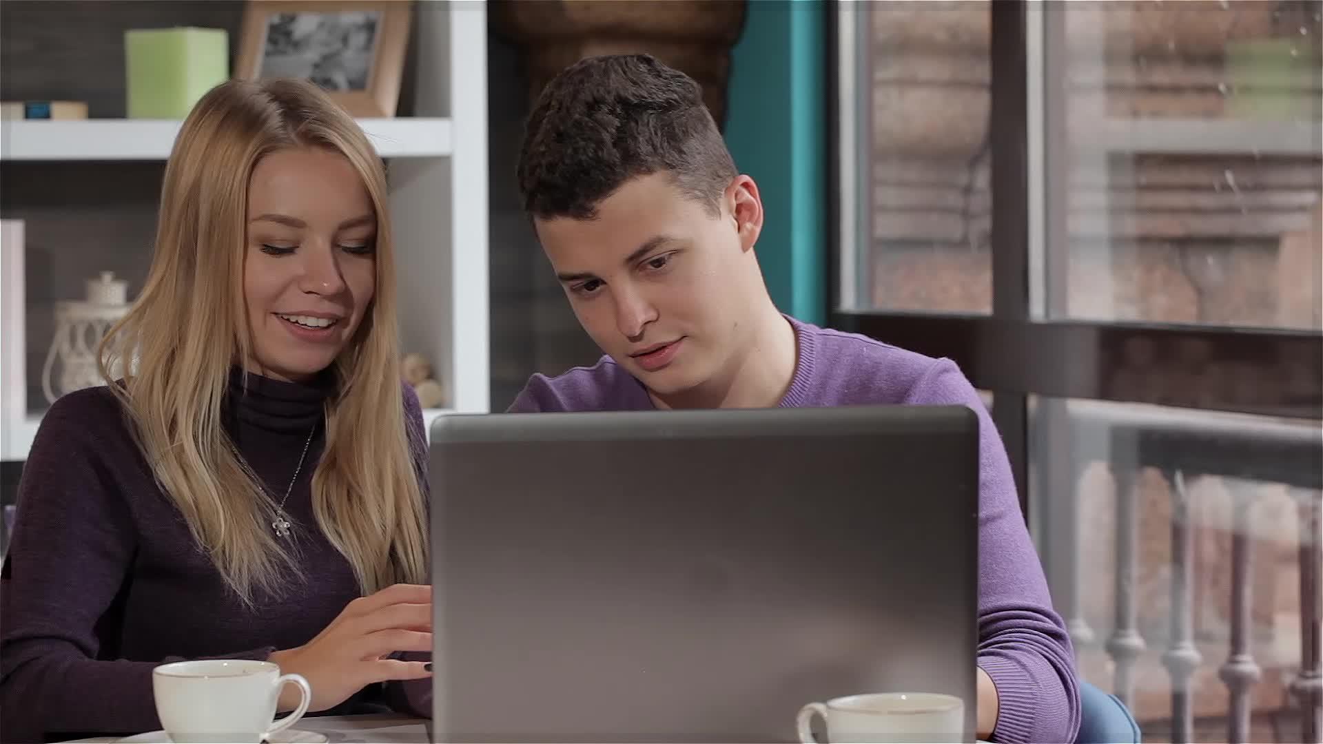一对夫妇在咖啡馆看笔记本电脑视频的预览图