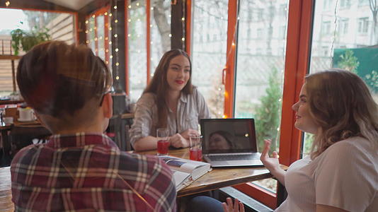 学习期间三名男女学生坐在咖啡馆里讨论他们坐在一张桌子上视频的预览图
