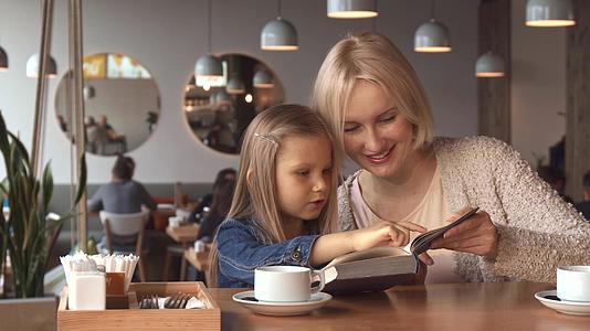 母亲和女儿在咖啡馆读书视频的预览图