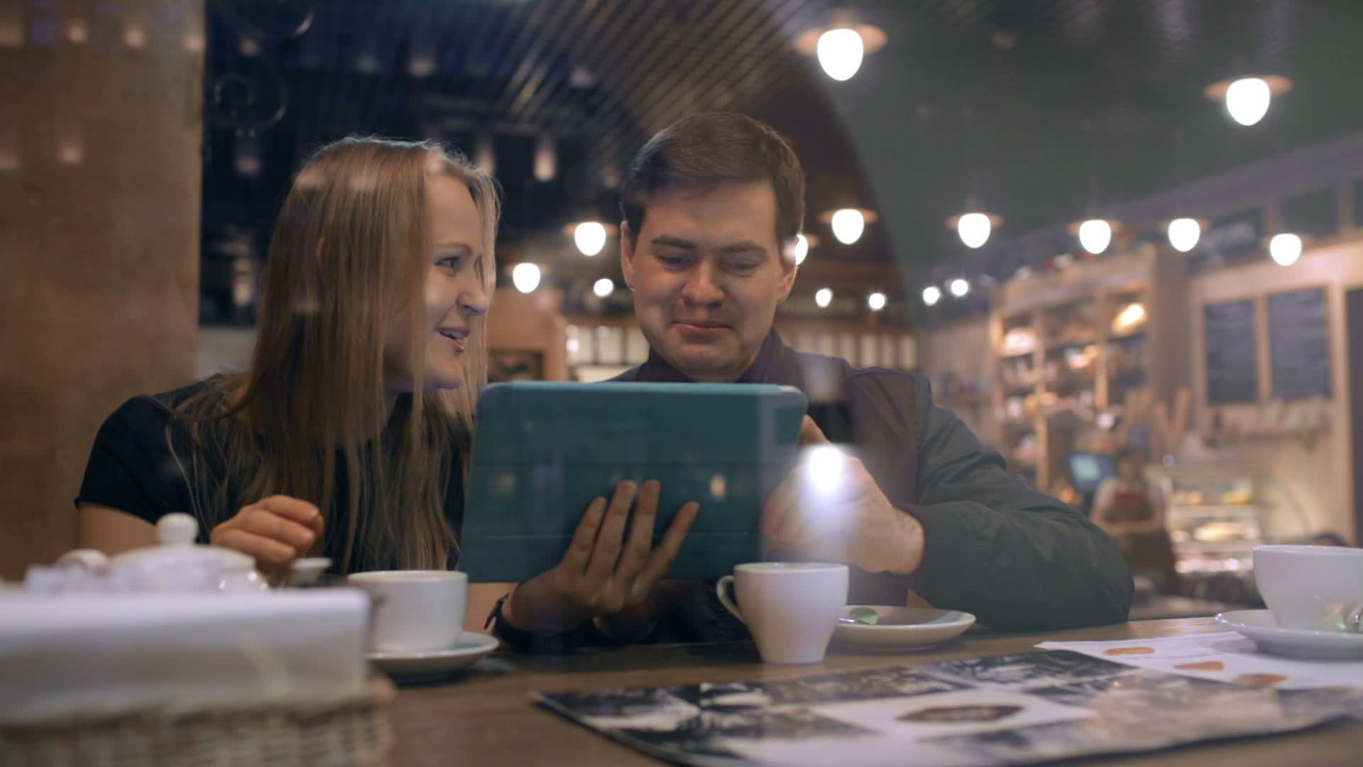 咖啡馆里的年轻人看着平板电脑说话视频的预览图