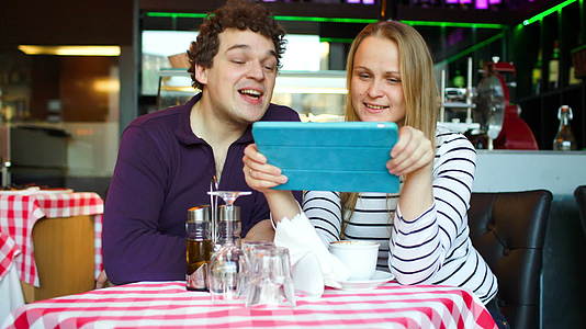 咖啡馆的年轻夫妇在平板电脑上聊天视频的预览图