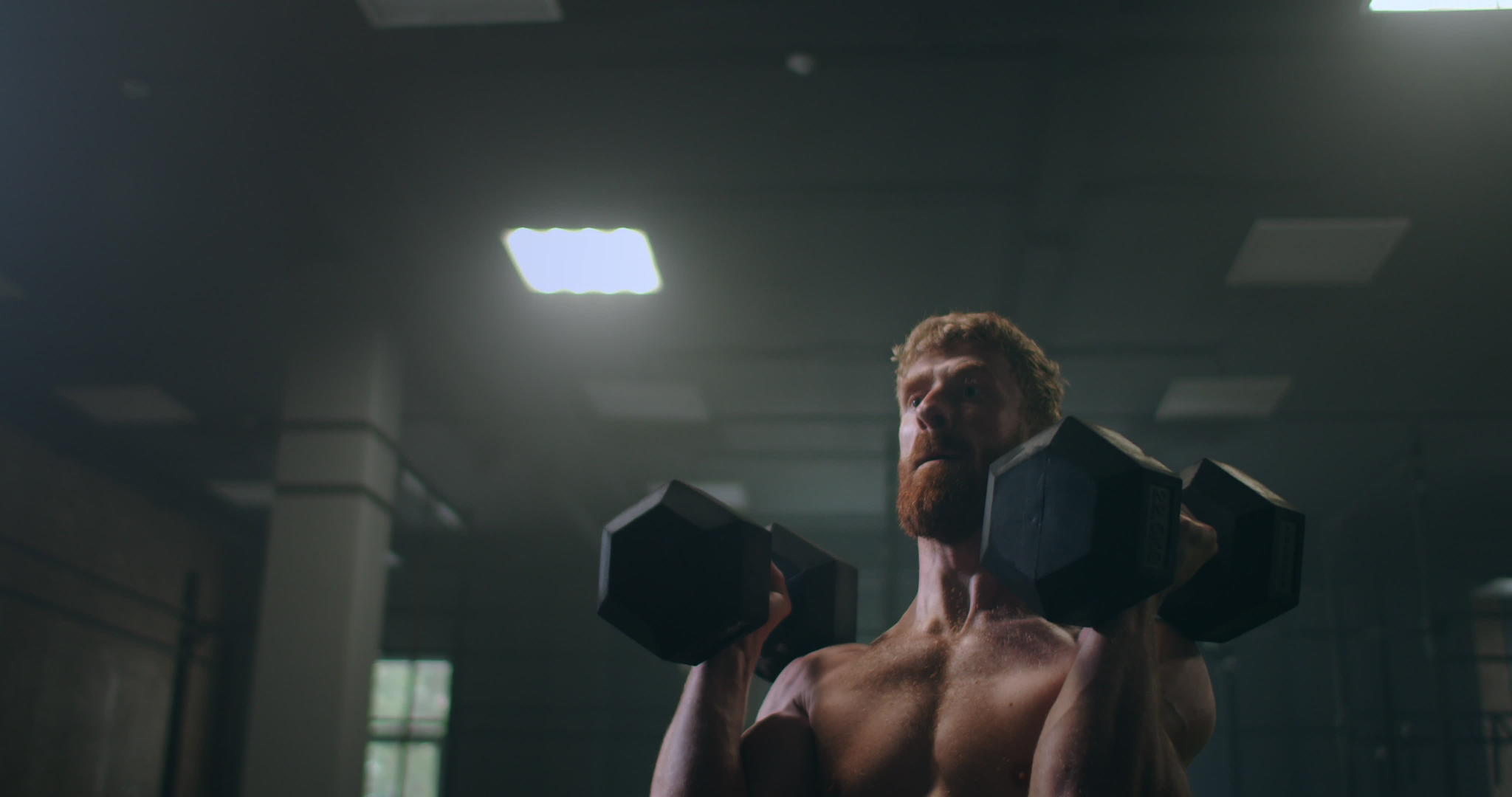 一个强壮的运动员慢慢地站在健身房里推着哑铃视频的预览图