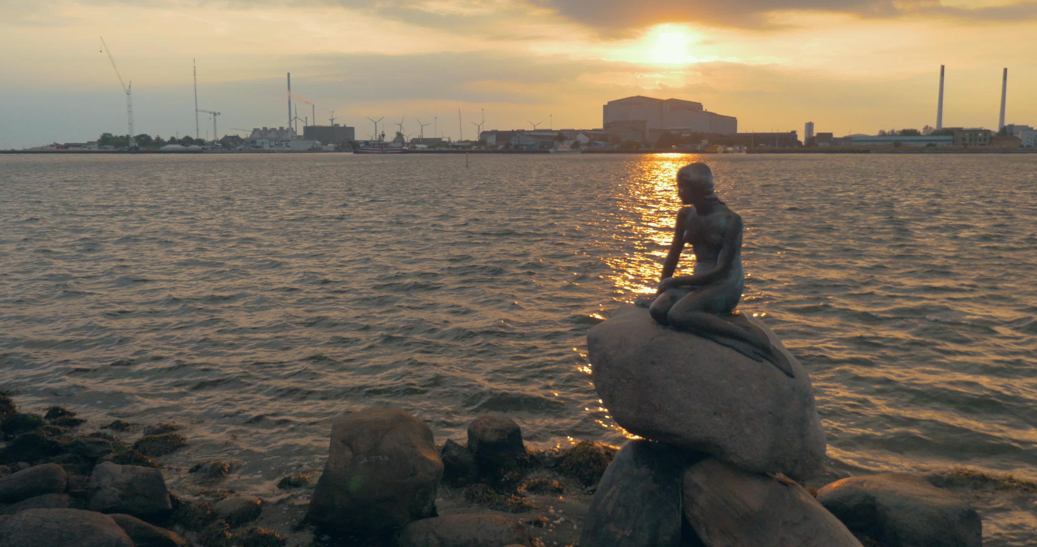 日落时在城市水边的美人鱼雕像视频的预览图