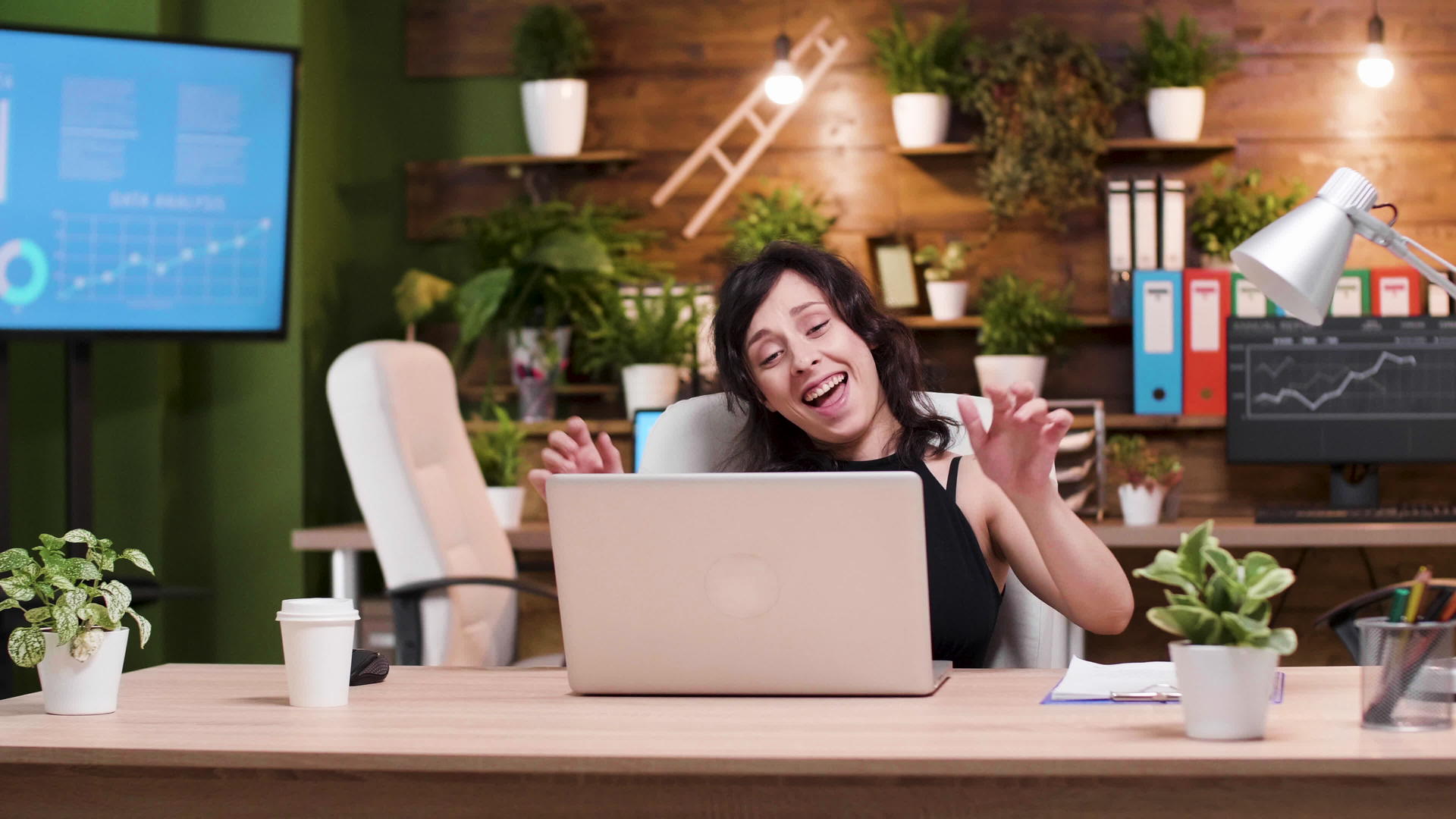 成功的年轻女商人在笔记本电脑前跳舞视频的预览图