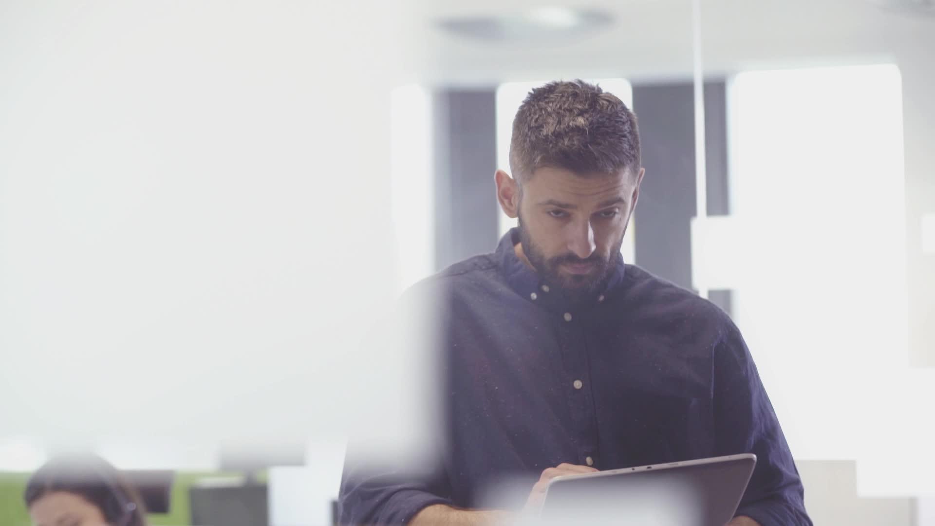 吸引人的胡子商人使用平板电脑在办公室工作视频的预览图