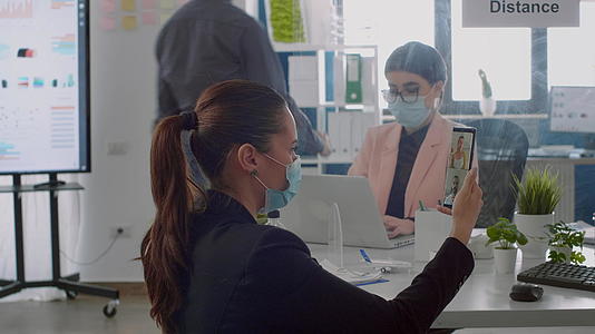 一位戴着保护性医用口罩的女商人在网像头上说话视频的预览图