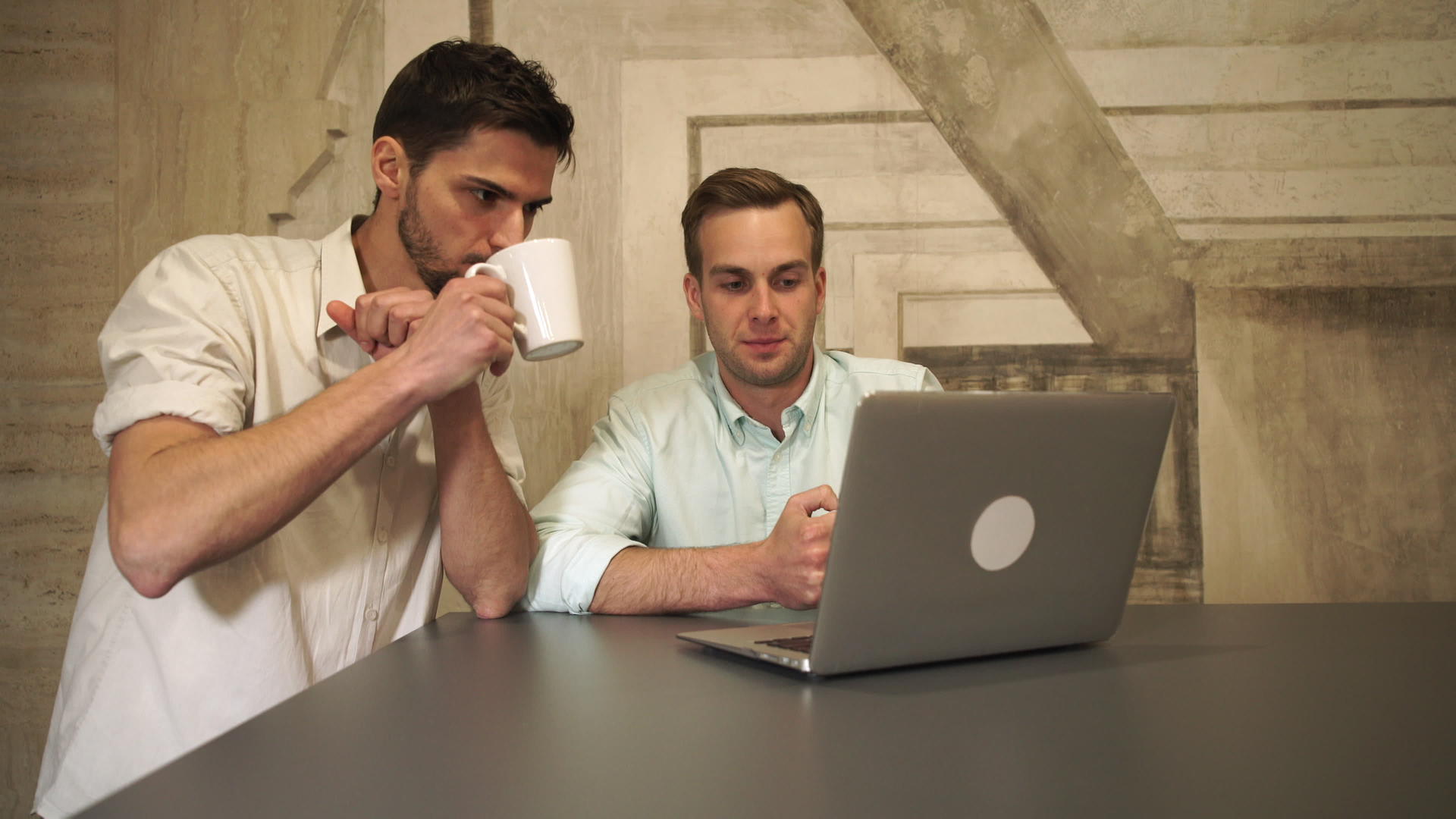 两个年轻人在咖啡馆里看着屏幕上的电脑谈笑风生视频的预览图