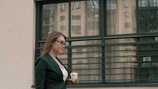 一个拿着咖啡杯的年轻女子走在城市街道上视频的预览图