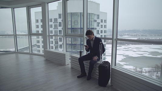 男人带着行李箱坐在办公楼里视频的预览图