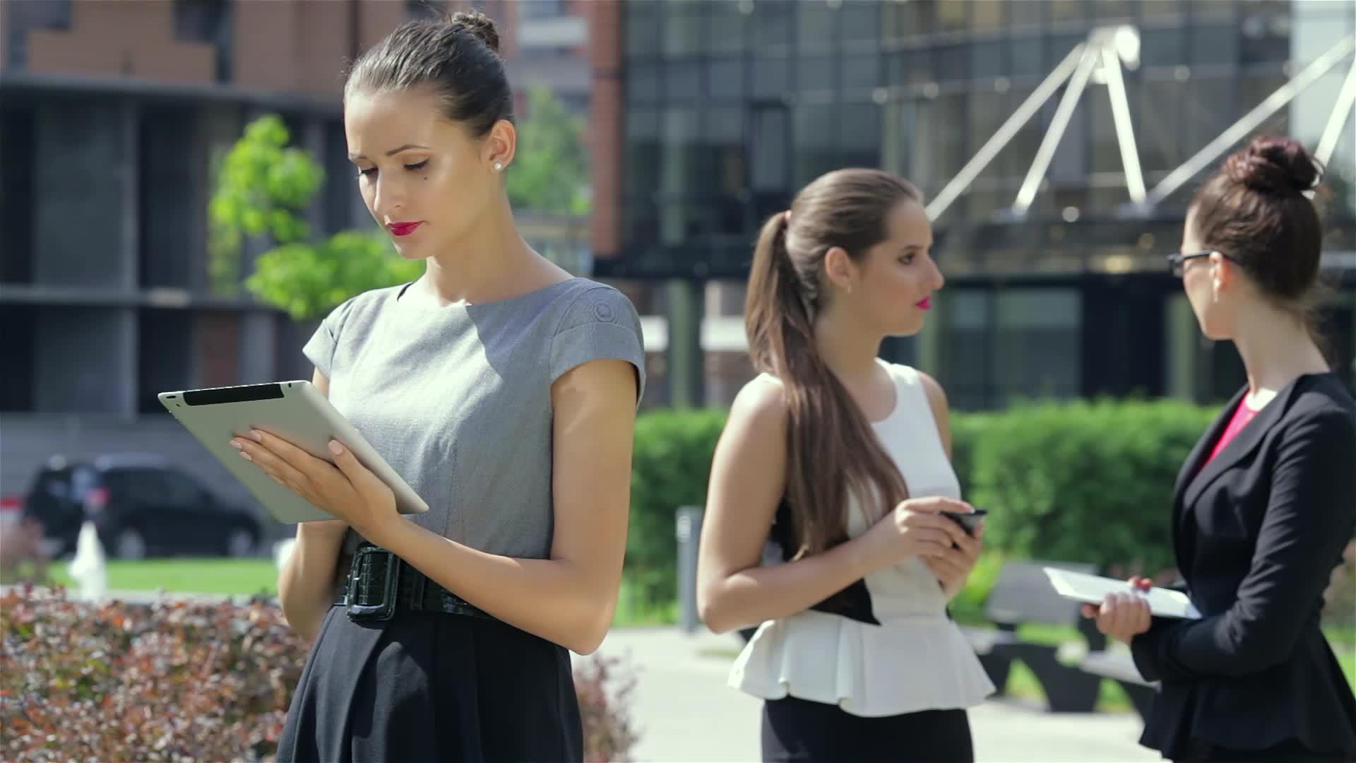 在她们的商业伙伴的背景下女商人在平板电脑上工作视频的预览图