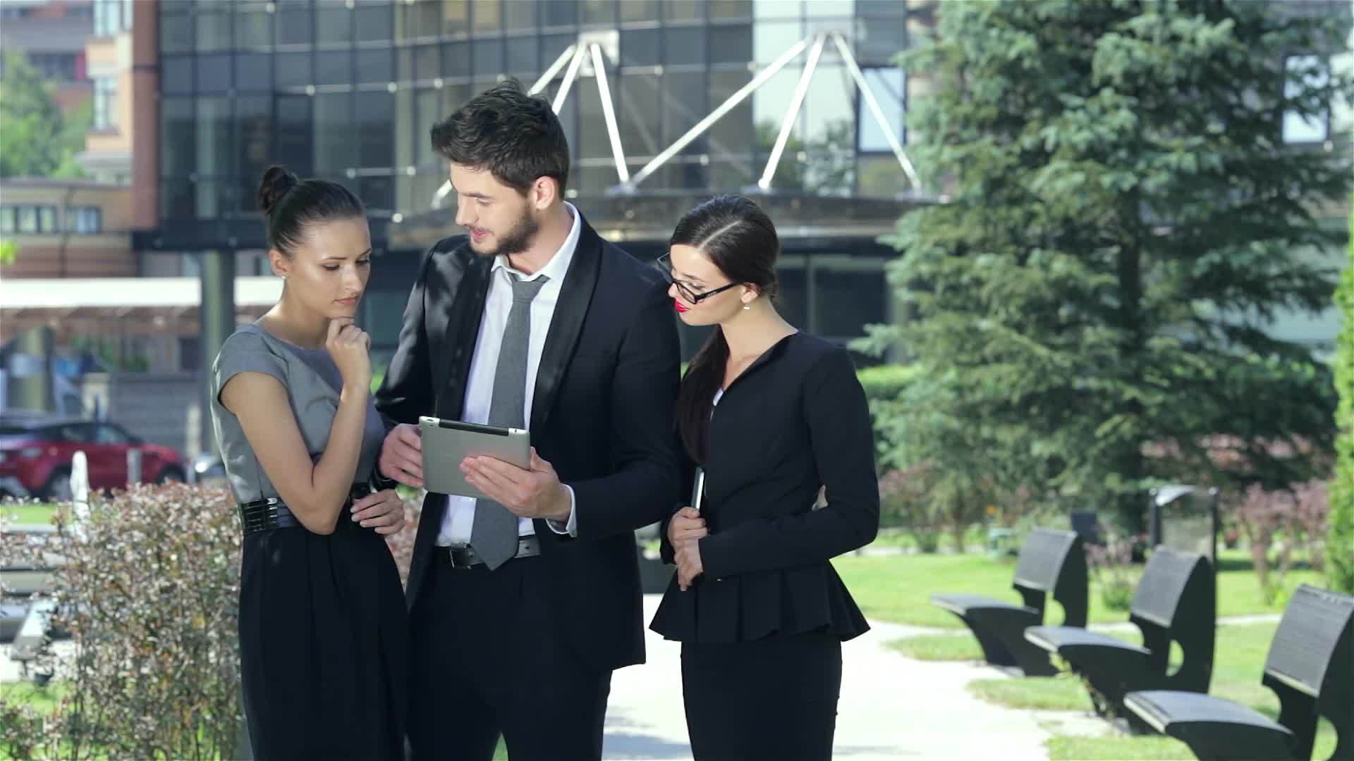 三个商业伙伴在一台平板电脑上工作以获得好消息和快乐视频的预览图