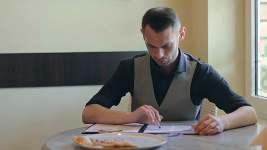 英俊的男人在披萨咖啡馆写文件视频的预览图